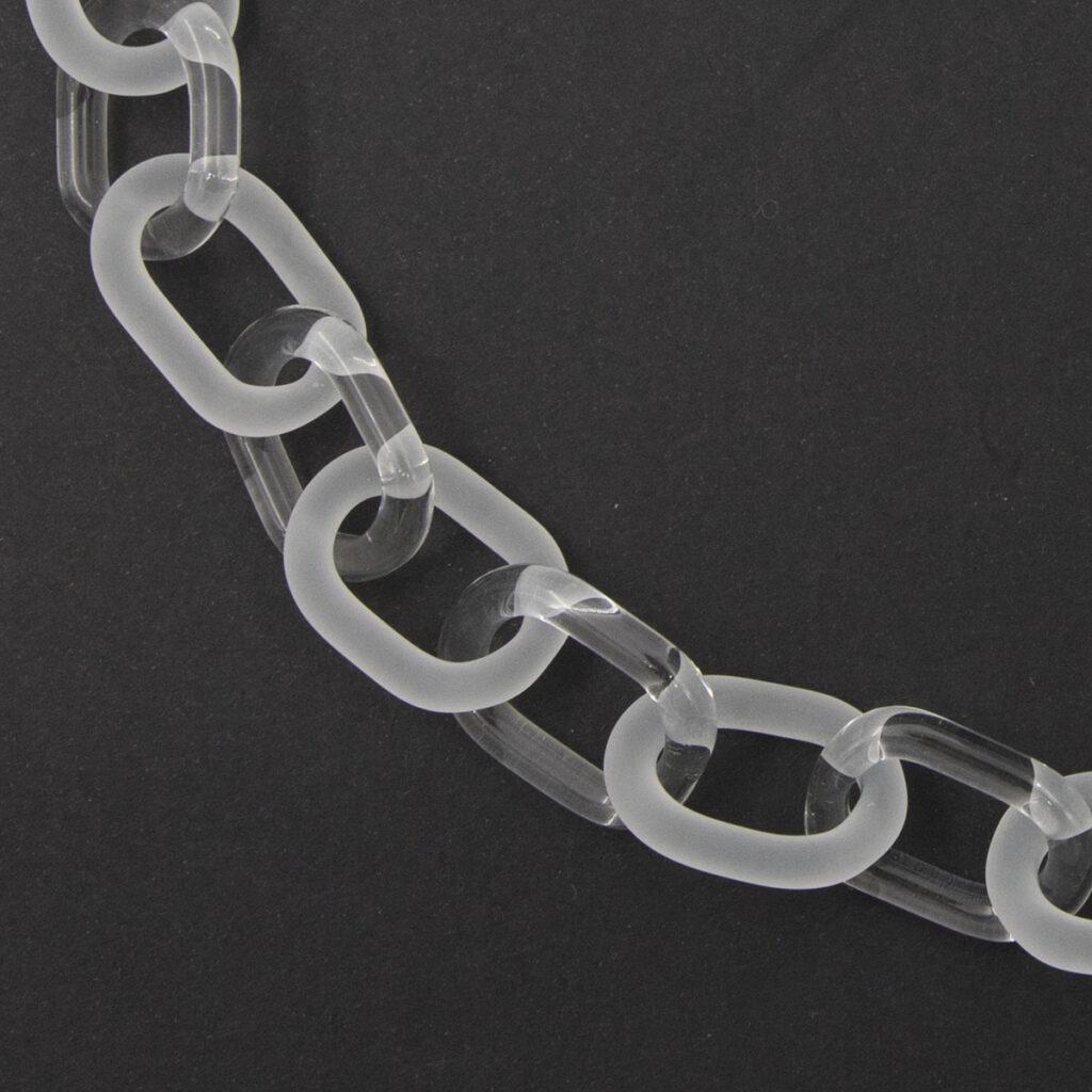 Close up of bold glass chain necklace made from alternating links of clear and frosted glass.