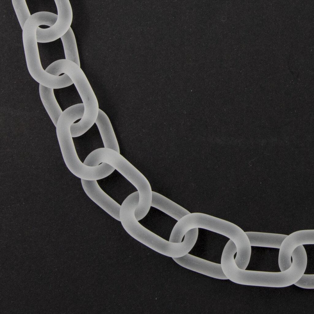 Close up view of bold glass chain necklace made from links of frosted glass laid flat in a circle.