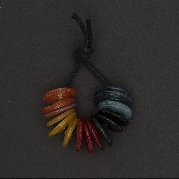 set of glass disk beads in oranges, yellows, reds, greens and blues, strung on a cord.