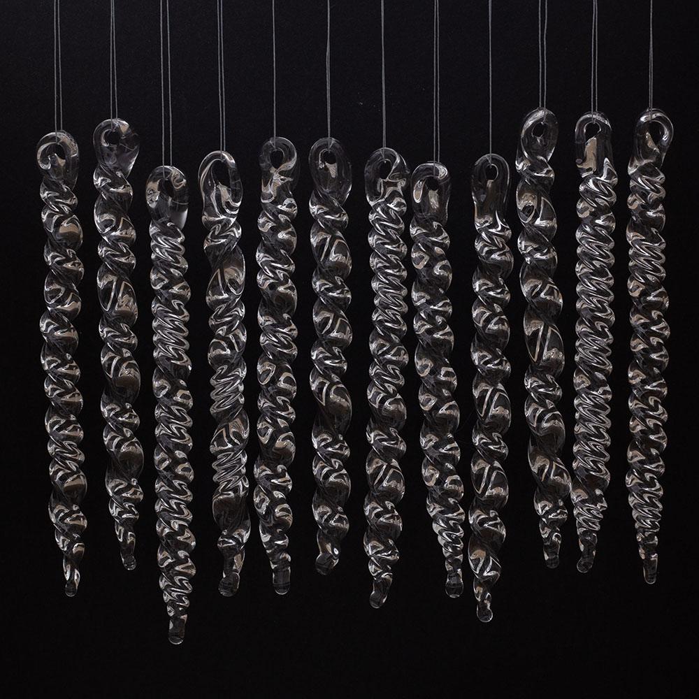 12 large clear glass icicles with hanging loop and twist design. The icicles hand in front of a black background.