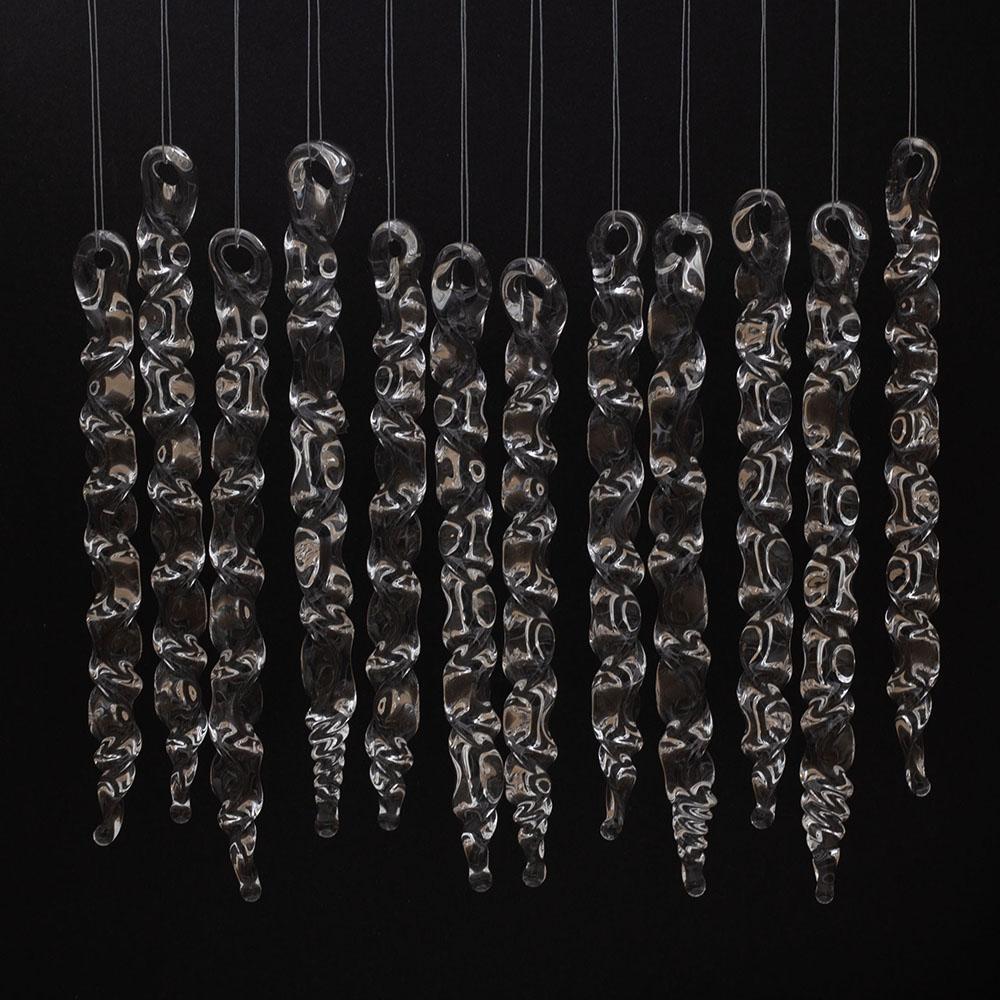 12 large clear glass icicles with hanging loop and zig zag design. The icicles hand in front of a black background.
