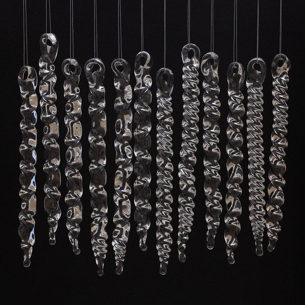 12 large clear glass icicles with hanging loop and zig zag design. The icicles hand in front of a black background.