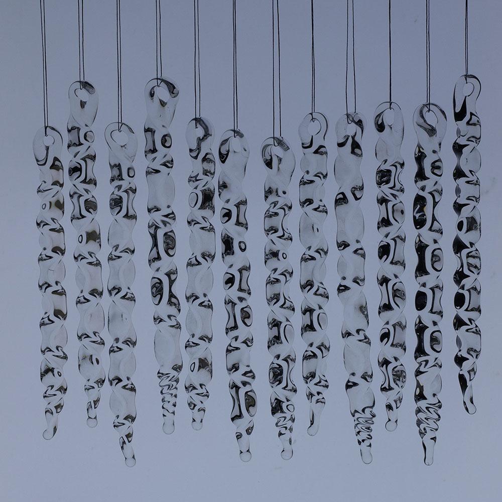 12 large clear glass icicles with hanging loop and zig zag design. The icicles hand in front of a frosty blue background.