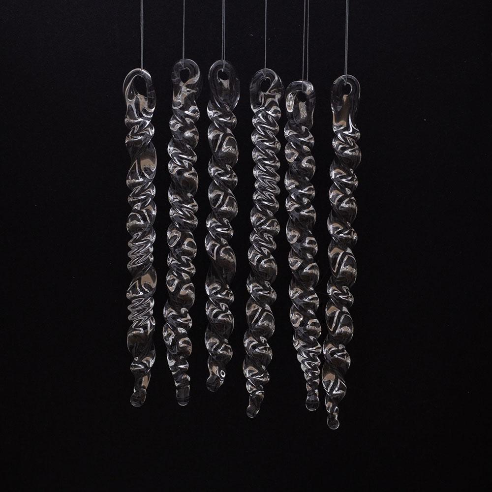6 large clear glass icicles with hanging loop and twist design. The icicles hand in front of a black background.