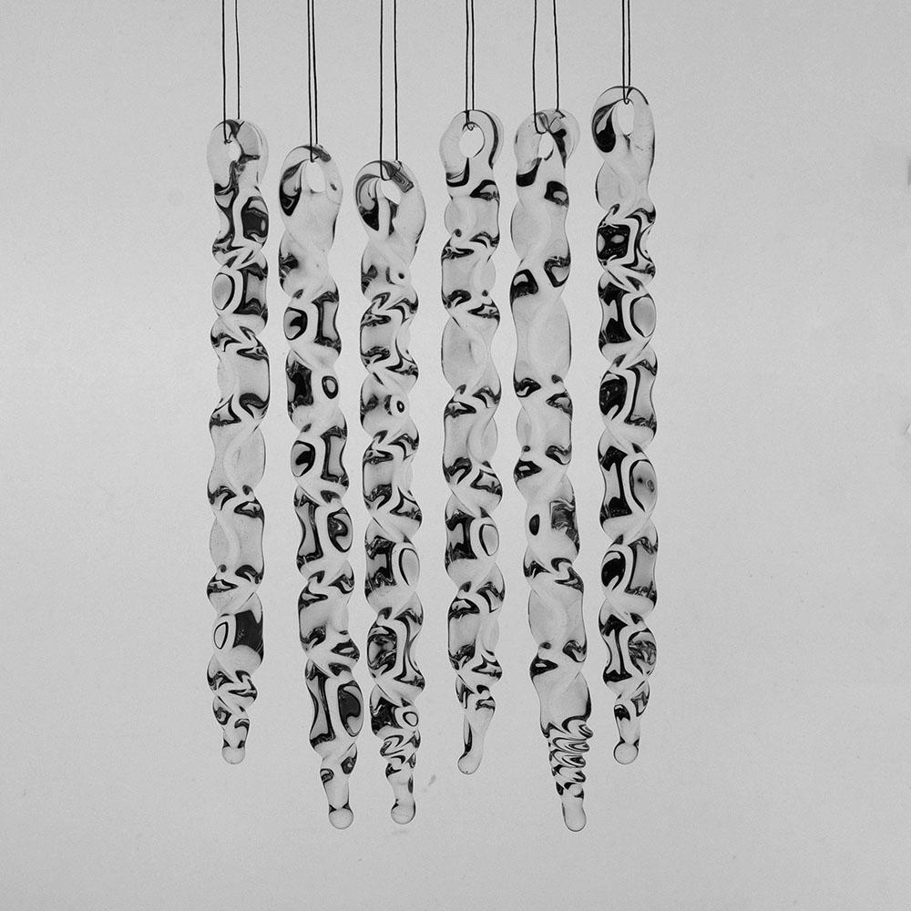 6 large clear glass icicles with hanging loop and zig zag design. The icicles hand in front of a pale grey background.