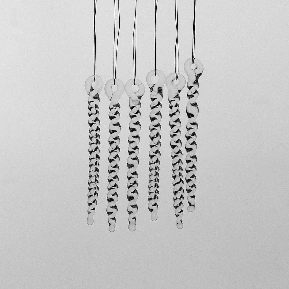 6 tiny clear glass icicles with hanging loop and twist design. The icicles hand in front of a pale grey background.