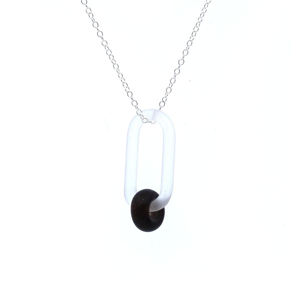 Close up view. A clear glass link which passes through a bead made from the transparent dark brown glass of a beer bottle. Link and beads have a frosted finish. The link hangs from a fine sterling silver chain.
