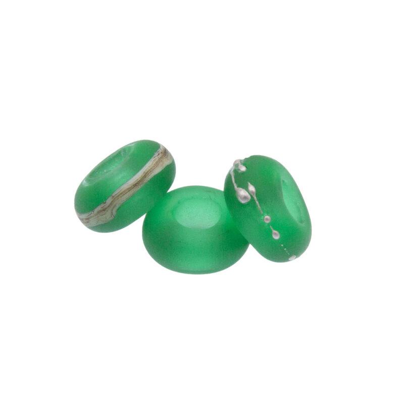 Three big hole beads made with transparent green glass. One bead is decorated with dots of fine silver, one with ivory glass and silver and the third is left plain. The beads have a frosted matt finish.