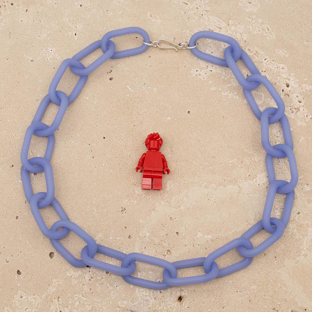 Frosted blue glass chain with a silver hook clasp sitting on a sandstone tile. Shown with a red lego figure for scale.