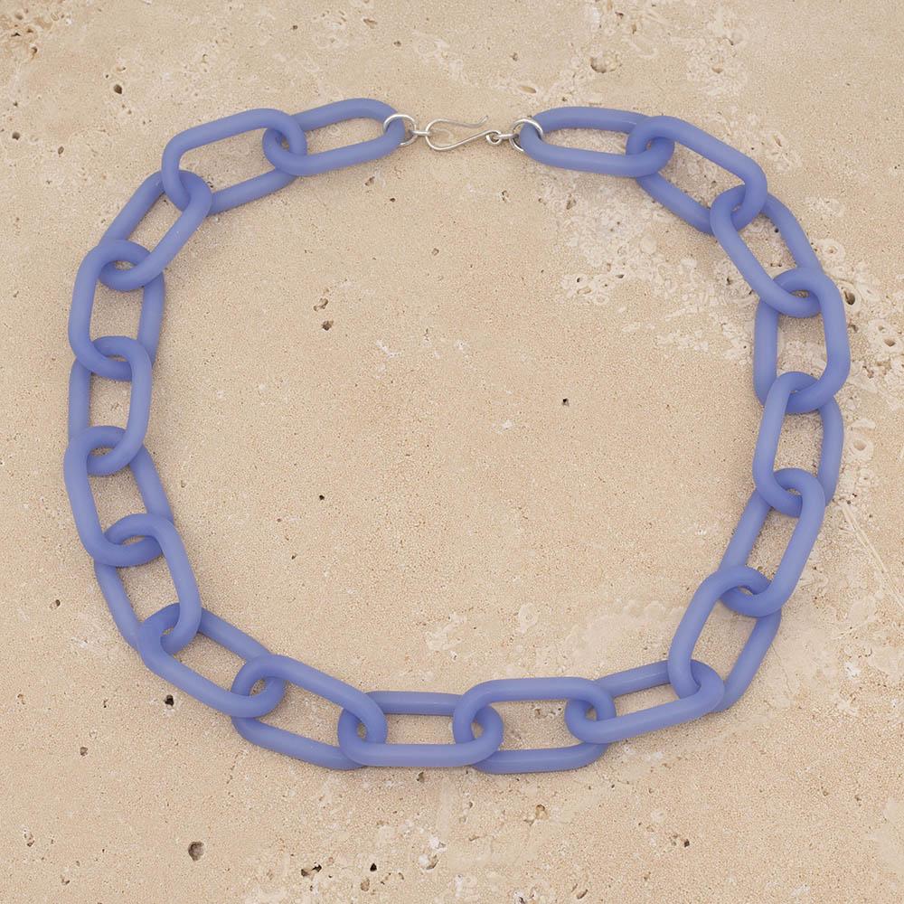 Frosted blue glass chain with a silver hook clasp sitting on a sandstone tile.