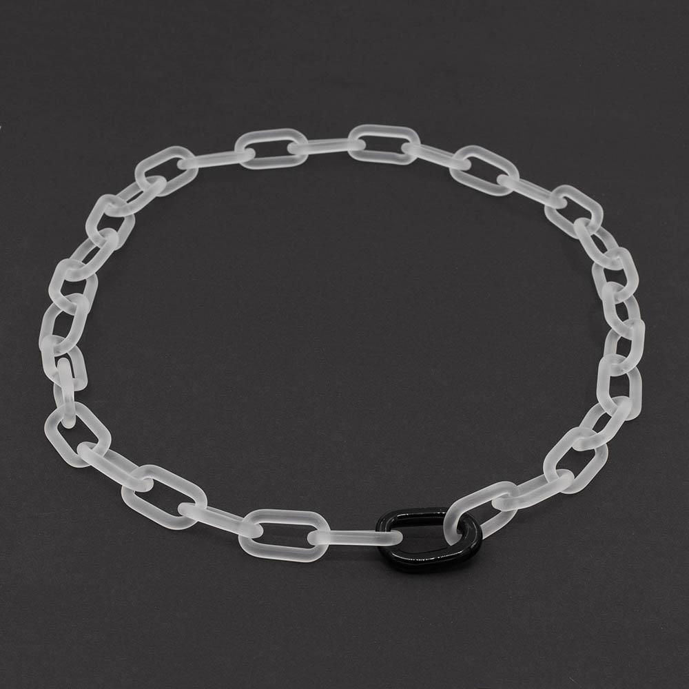Frosted clear glass chain with a single black link sitting on a dark background.