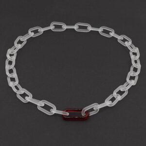 Frosted clear glass chain with single red link necklace sitting on a dark background.