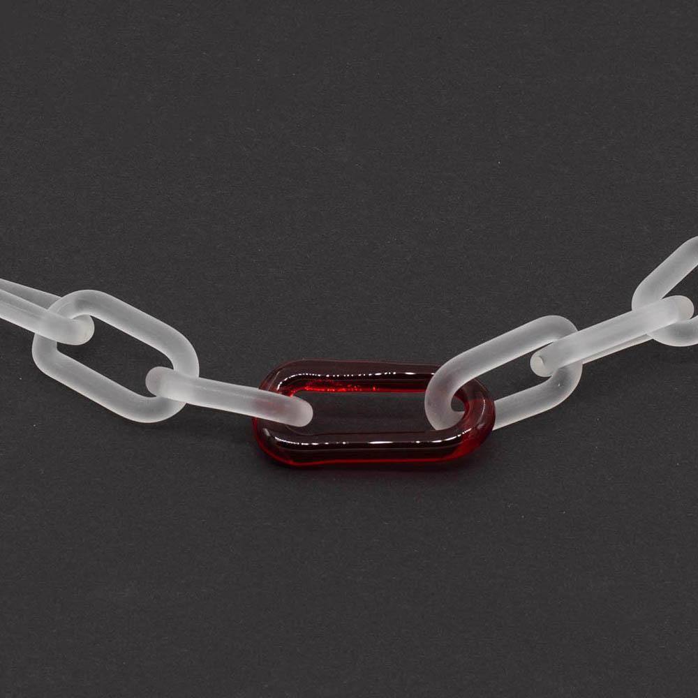 Close up of frosted clear glass chain with single red link necklace on a dark background.