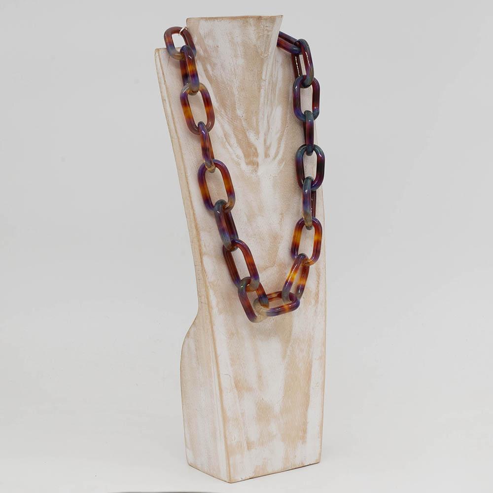 Transparent multicolour glass chain link necklace with a sterling silver hook and loop catch. Each link has blue, yellow, orange, purple and pink. The necklace sits on a whitewashed wooden torso which faces sideways.