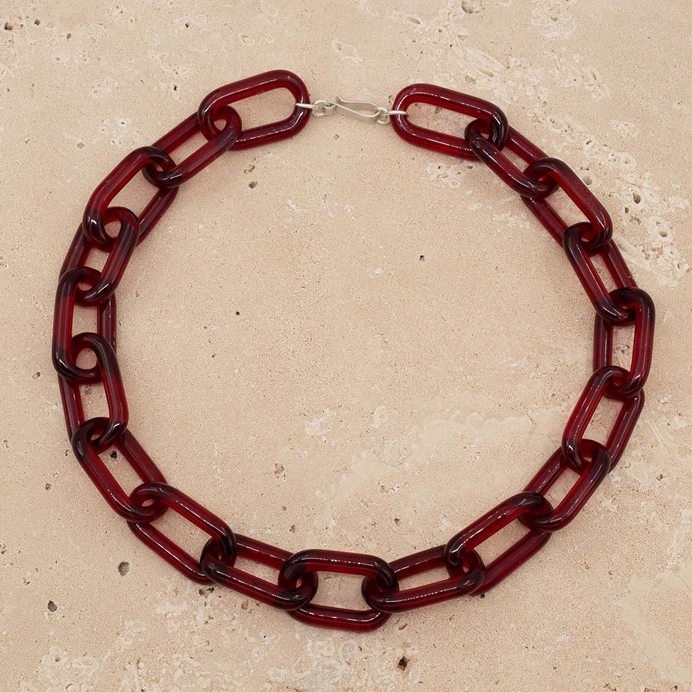 Transparent red glass chain link necklace with a sterling silver hook and loop catch. The necklace sits on a sandstone tile.