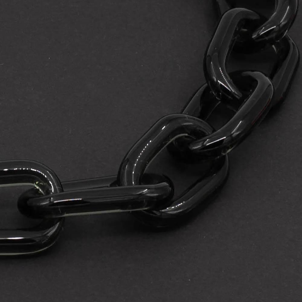 Close up of transparent black glass chain link necklace on a dark background