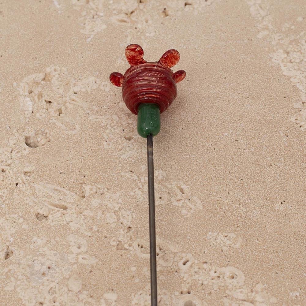 Back view of bee sipper in red glass with red petals and dark yellow centre showing green stem and stainless steel rod.