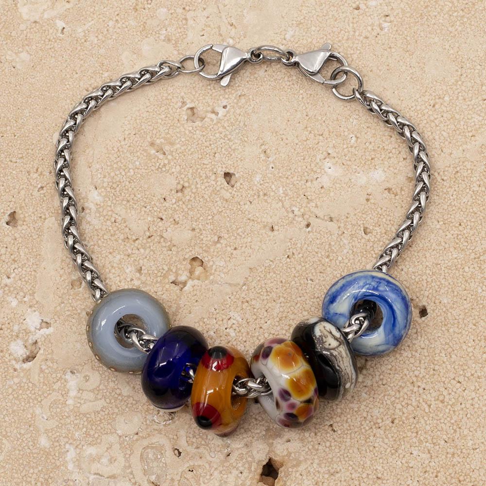 6 big hole beads on a stainless steel chain bracelet with double lobster clasp fastening. The beads are swirled blue and ivory, black with a band of ivory, pale grey with speckles of orange and pink, gold with raised red and black dots, dark blue with a clear dot and pale blue with dots of fine silver.