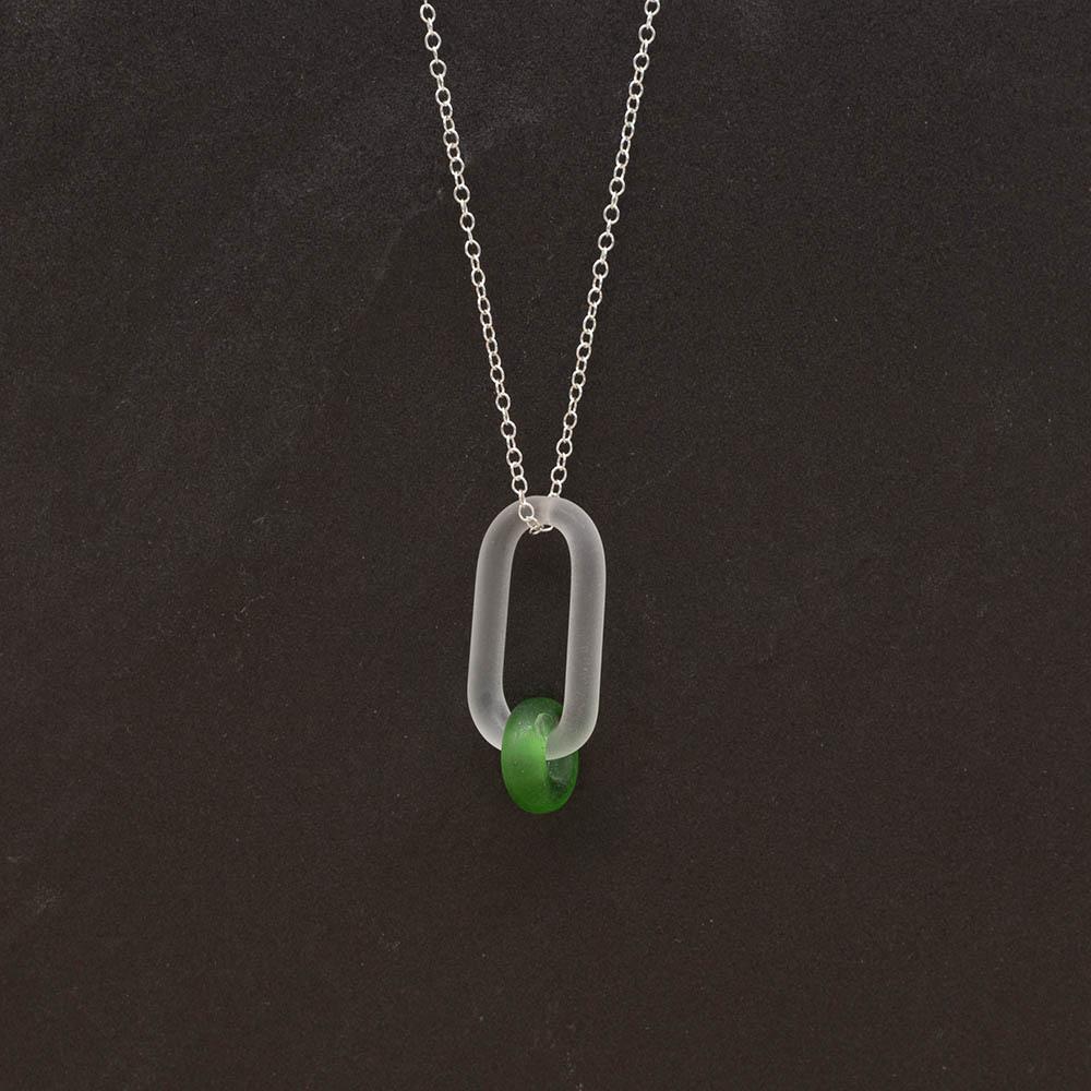 A frosted glass link which passes through a bead made from a green Gordons gin bottle. The link hangs from a silver chain. Shown on a slate background.