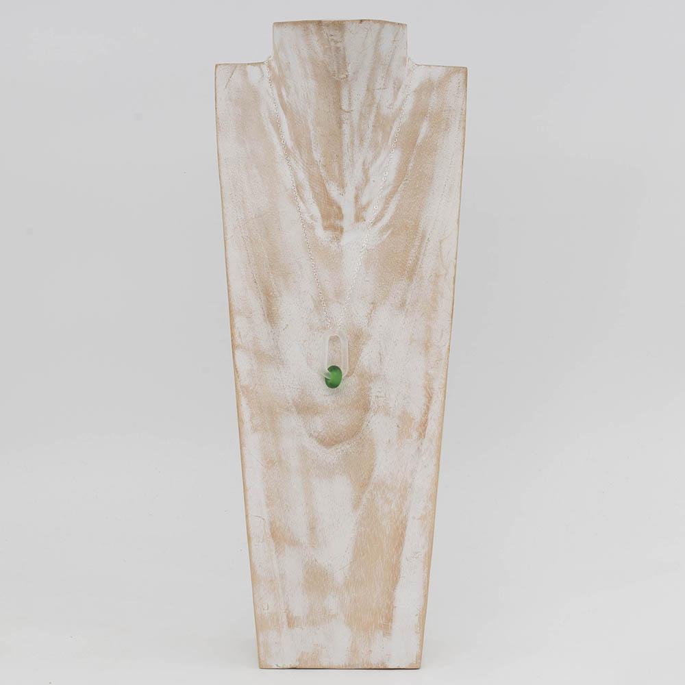 A frosted glass link which passes through a bead made from a green Gordons gin bottle. The link hangs from a silver chain. Shown on a whitewashed wooden torso.