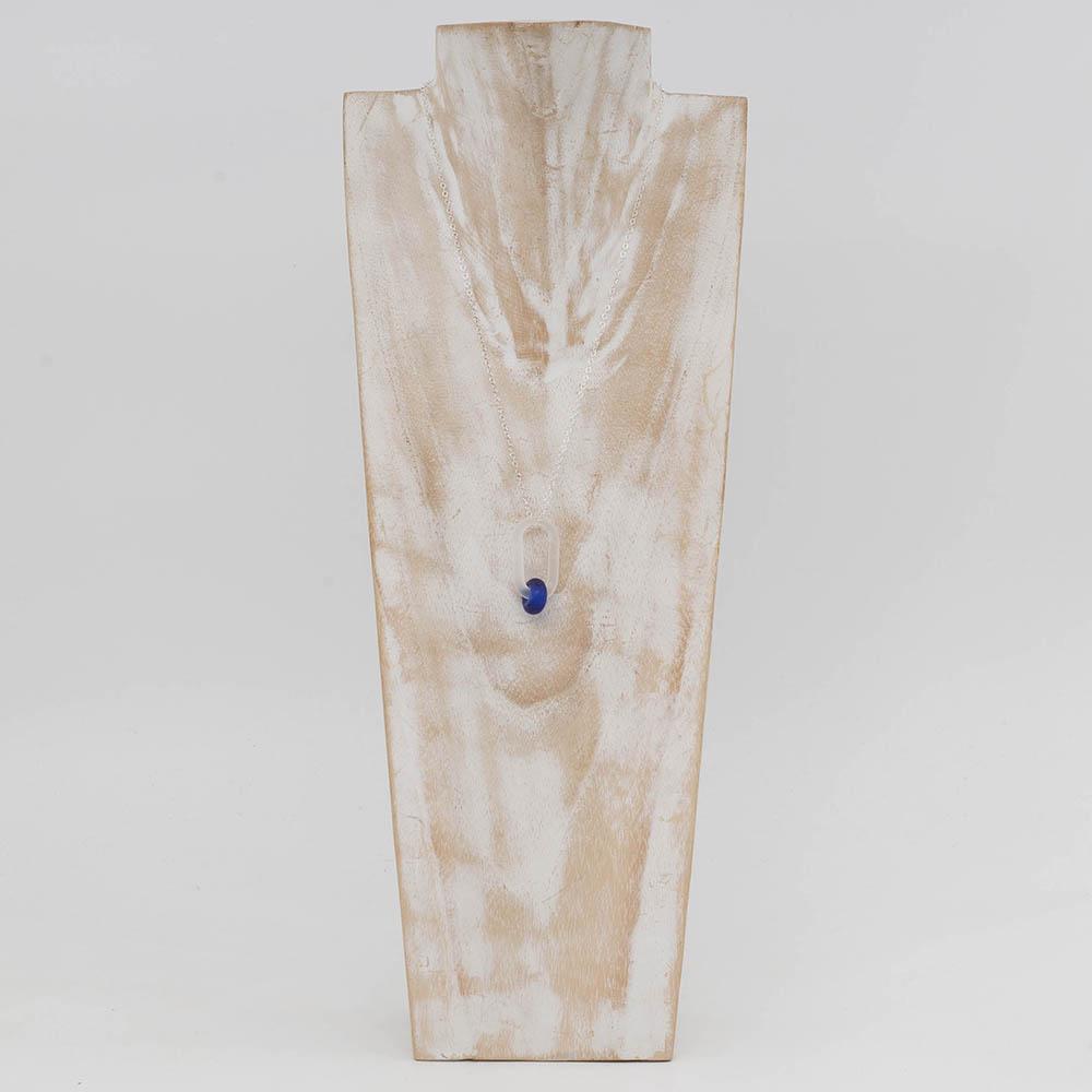 A frosted glass link which passes through a bead made from bright blue sherry bottle glass. The link hangs from a silver chain. Shown on a whitewashed wood torso.