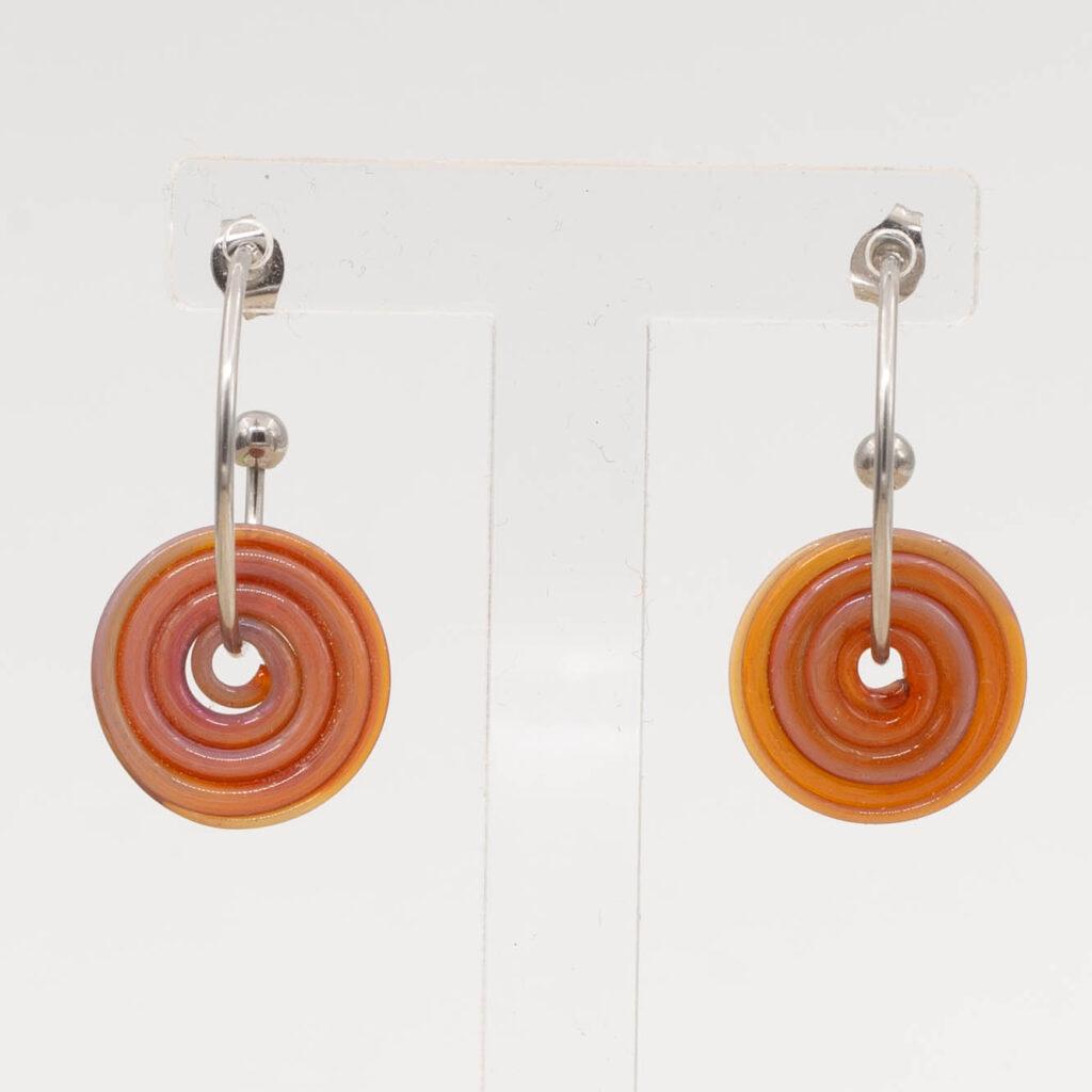 Front view of amber-purple glass disc hanging on a stainless steel hoop earring with a butterfly back.