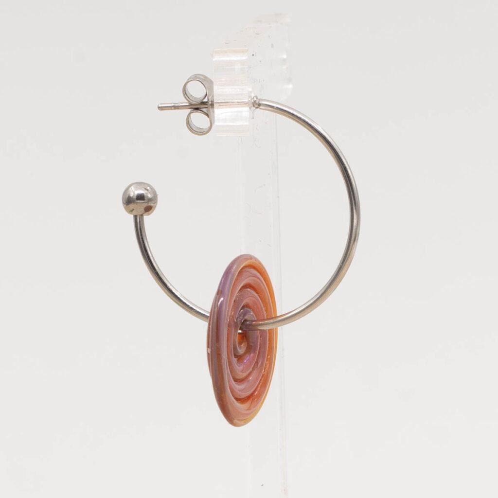 Side view of amber-purple glass disc hanging on a stainless steel hoop earring with a butterfly back.