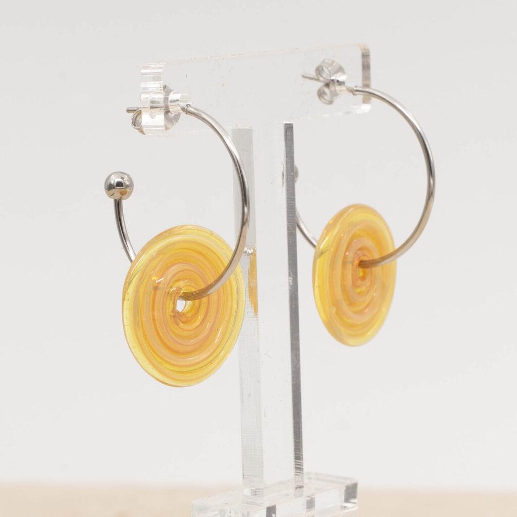 Side view of grapefruit yellow glass disc hanging on a stainless steel hoop earring with a butterfly back.