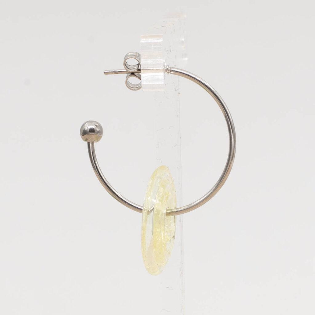 Side view of pale yellow glass disc hanging on a stainless steel hoop earring with a butterfly back.