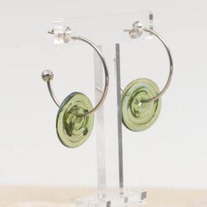 Side view of transparent green glass disc hanging on a stainless steel hoop earring with a butterfly back.