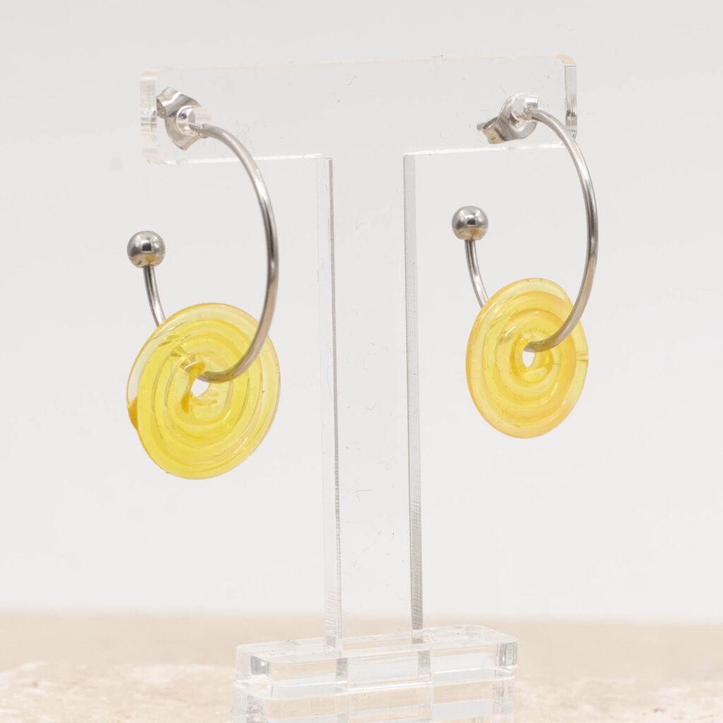 A sunshine yellow glass disc hanging on a stainless steel hoop earring with a butterfly back.