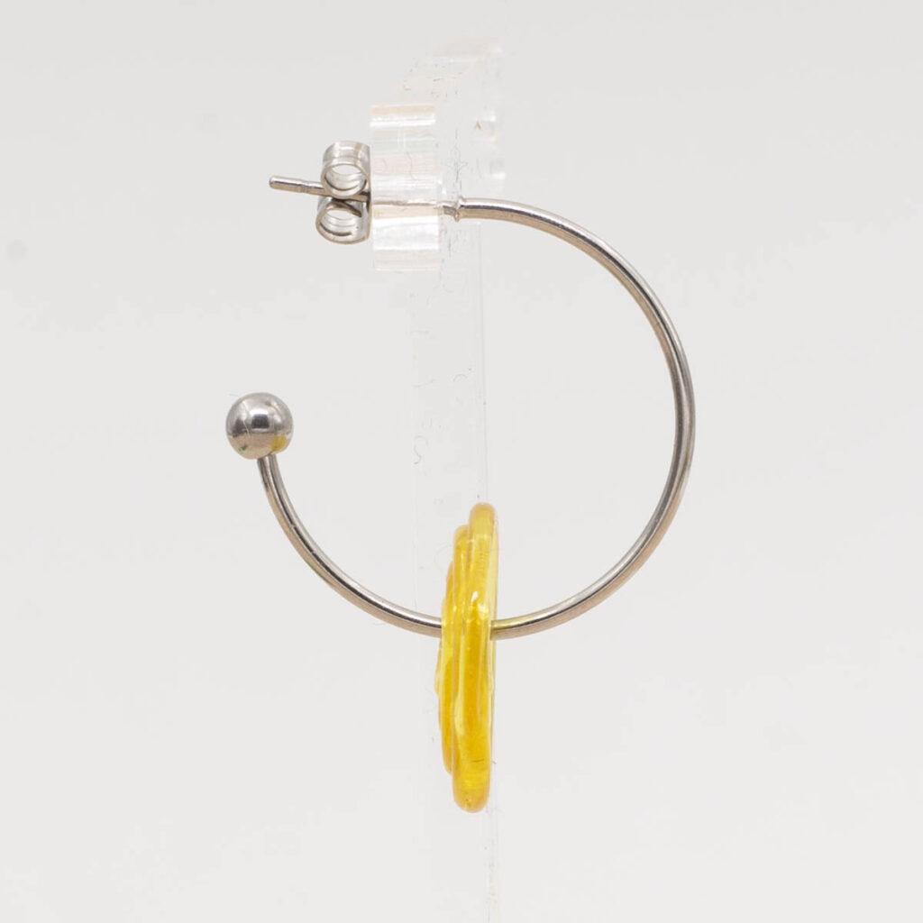 Side view of sunshine yellow glass disc hanging on a stainless steel hoop earring with a butterfly back.