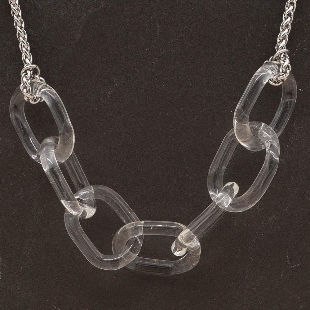 Close up of necklace with seven clear glass links. The links are fastened to a chain to make a necklace. Shown on a slate background.