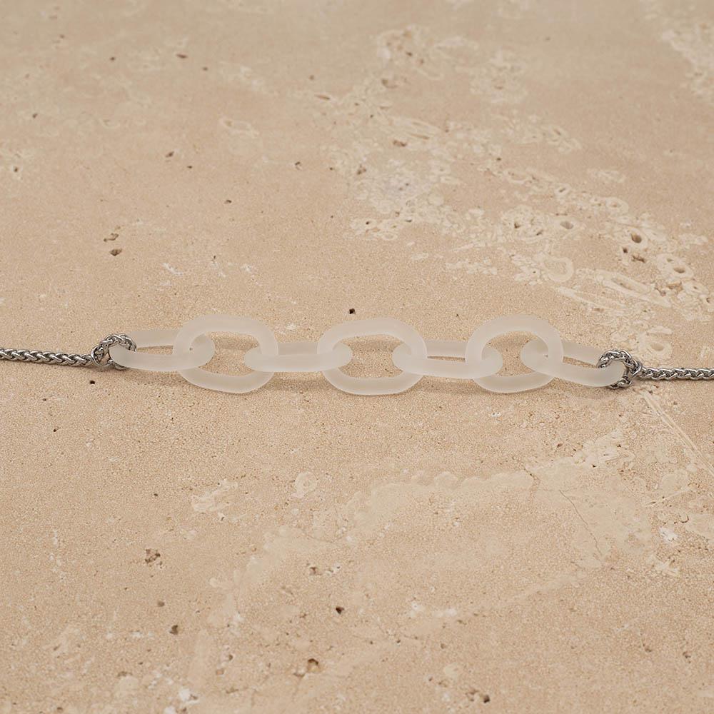 Close up of necklace with seven frosted glass links. The links are fastened to a chain to make a necklace. Shown on a sandstone background.