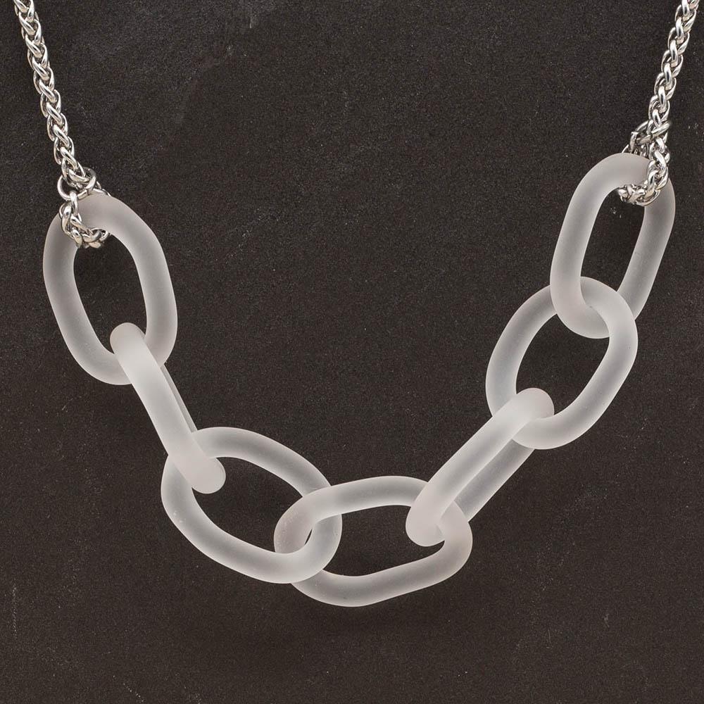 Close up of necklace with seven frosted glass links. The links are fastened to a chain to make a necklace. Shown on a slate background.