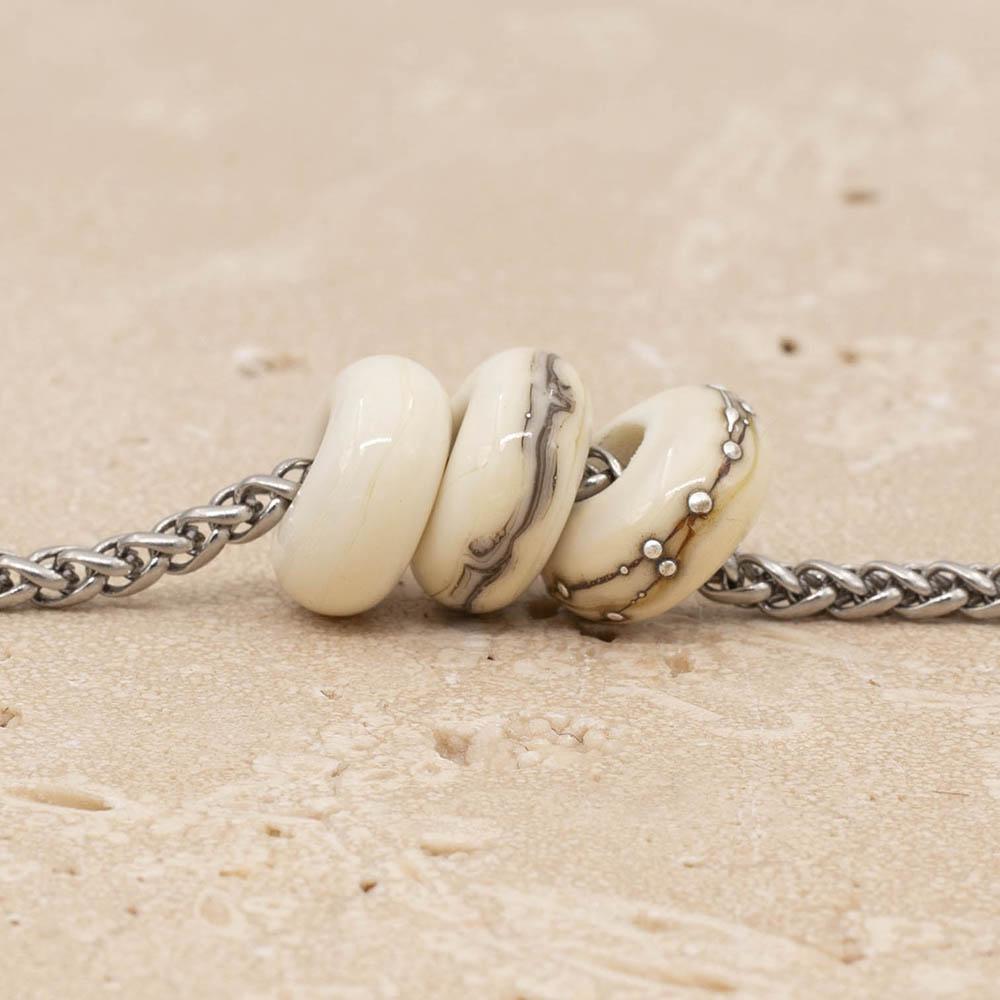 Close up of 3 shiny ivory glass beads with big holes on a stainless steel chain.