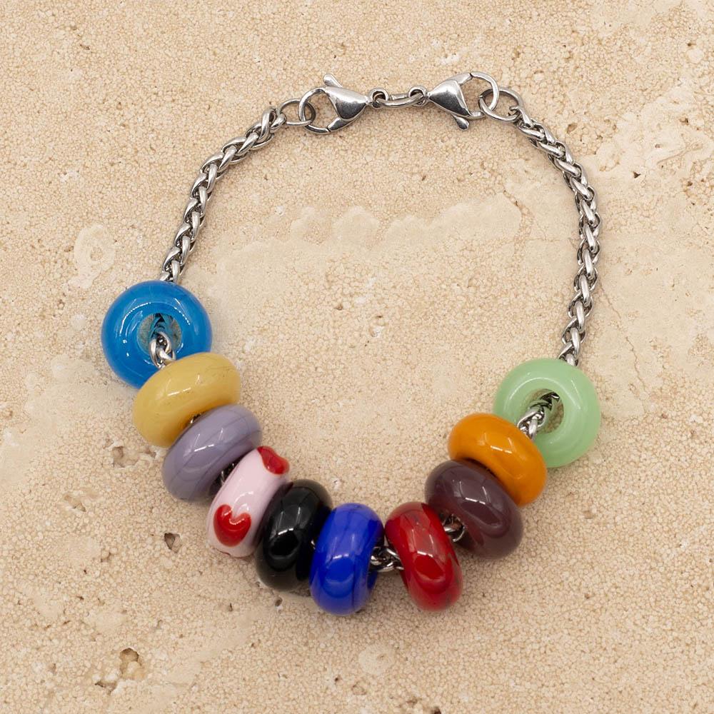 10 beads representing the Taylor Swift Eras Tour on a stainless steel chain bracelet with double lobster clasp fastening. The colours are pale green, gold, deep purple, red, bright blue, black, pale pink with red hearts, lilac, pale yellow and bright turquoise.