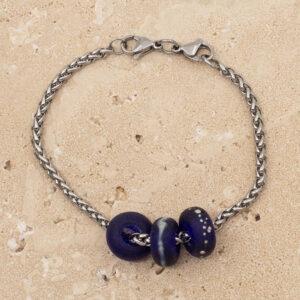Close up of 3 frosted cobalt blue glass beads with big holes on a stainless steel chain bracelet with double lobster clasp fastening.