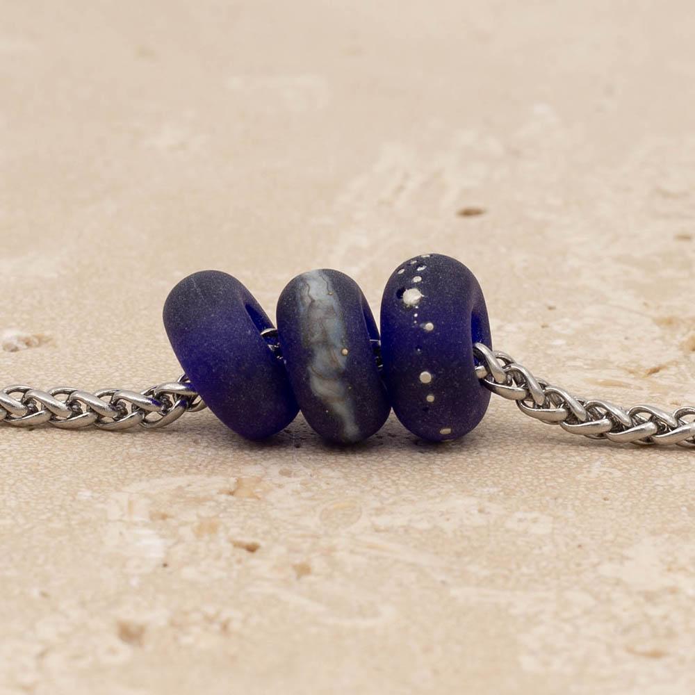 Close up of 3 frosted cobalt blue glass beads with big holes on a stainless steel chain.
