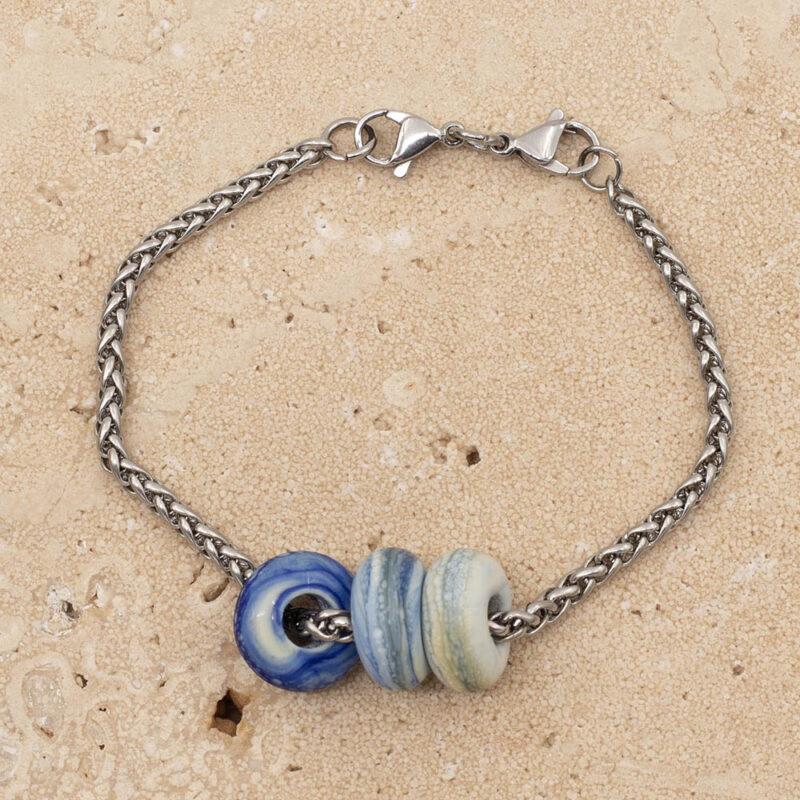 3 frosted ivory and blue glass beads with big holes on a stainless steel chain bracelet with double lobster clasp fastening.