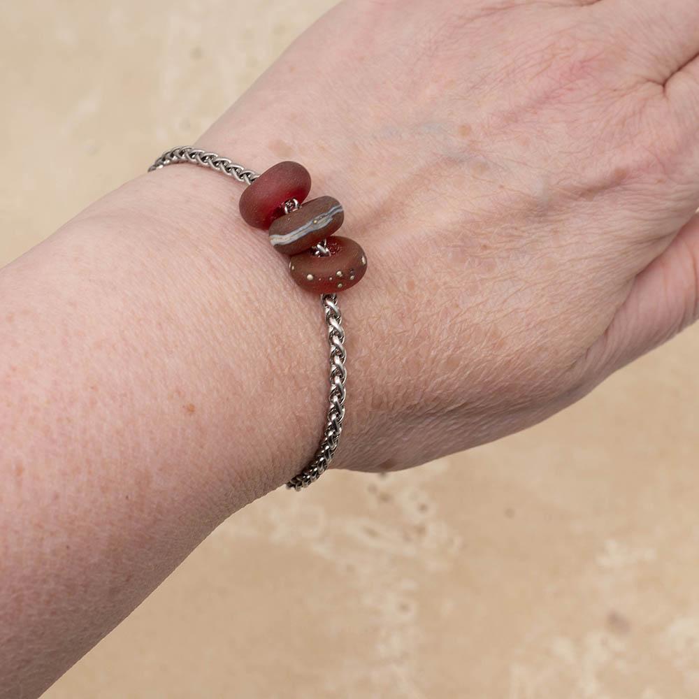 3 frosted pink glass beads with big holes on a stainless steel chain bracelet, shown worn on a wrist.
